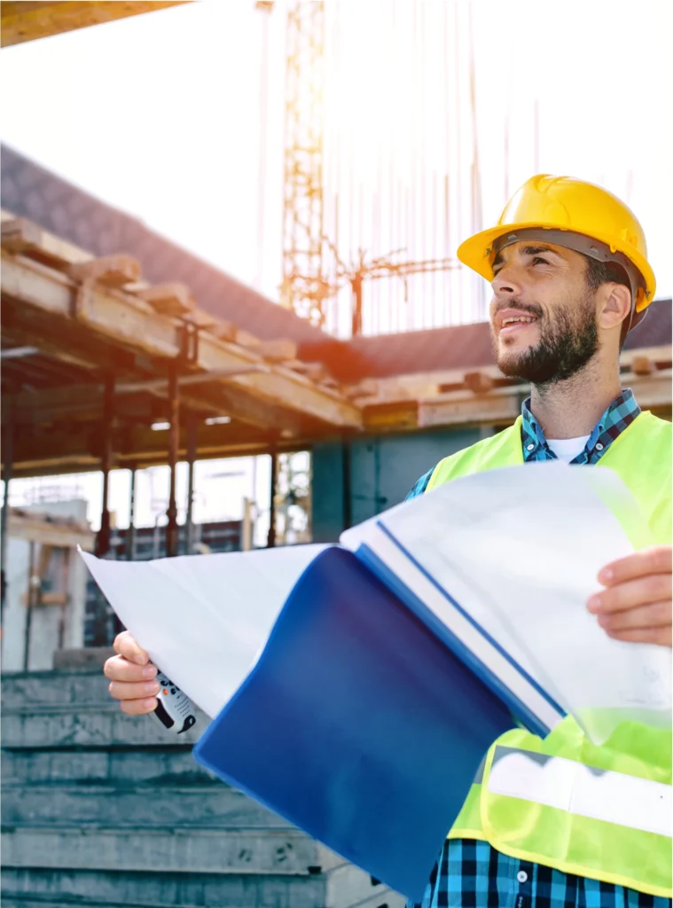 Project engineer in a hard hat reviewing plans on an active jobsite